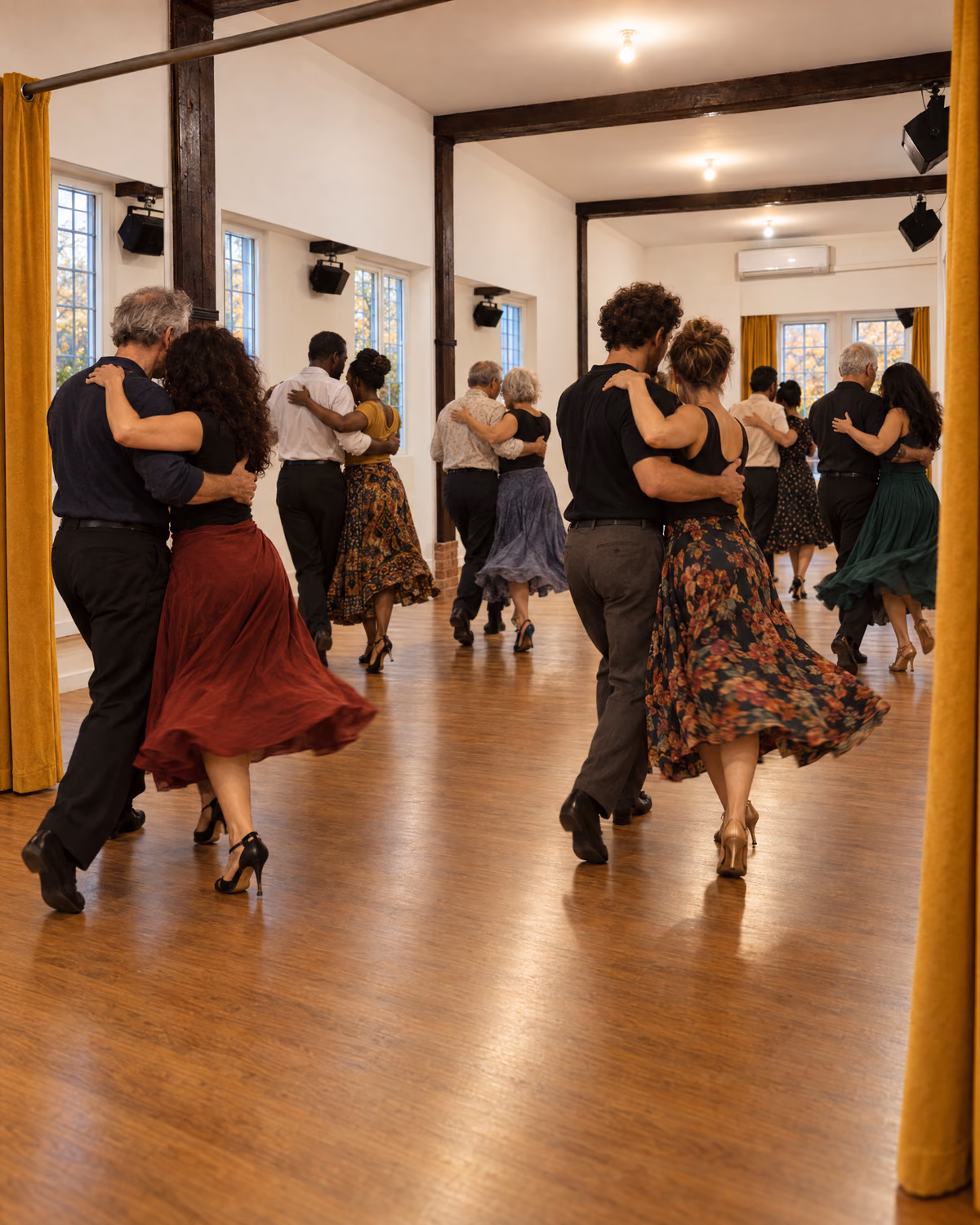 Cinq couples dansent dans la salle safran de l’école, jupes en mouvement, la lumière d’automne entrant par les fenêtres.