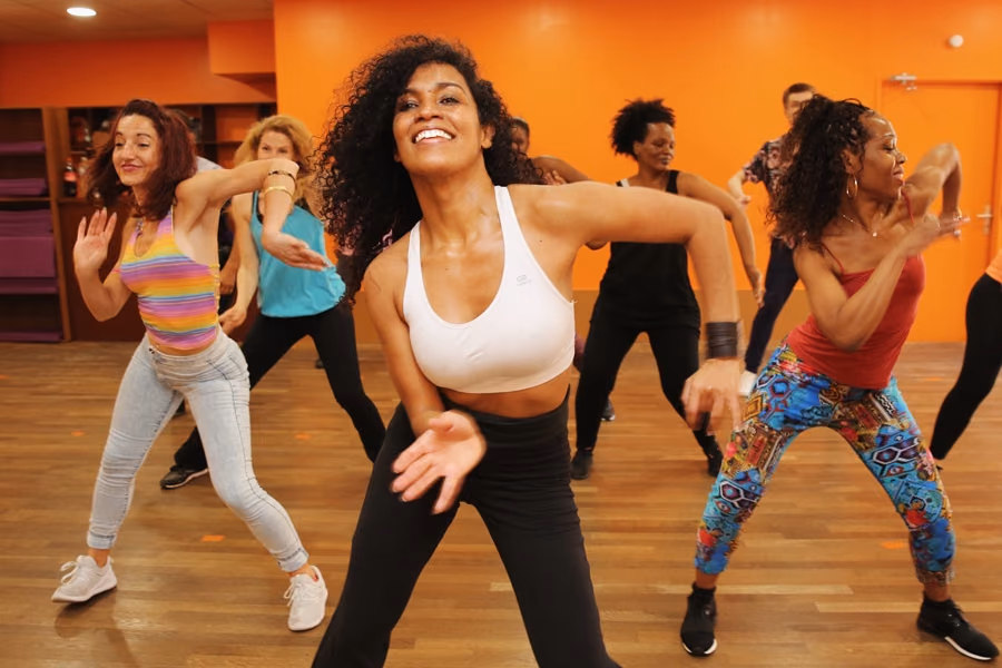 Cours de latin training : des danseuses en appui, bras tendus, dans la salle orange.
