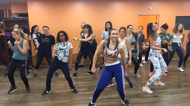 Cours collectif : une vingtaine de danseuses en mouvement devant les miroirs.