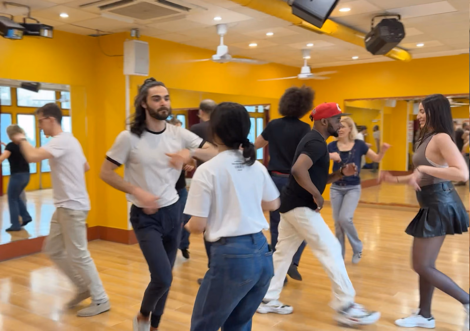 Une vingtaine de personnes enchaînent un pas en ligne dans la salle jaune.