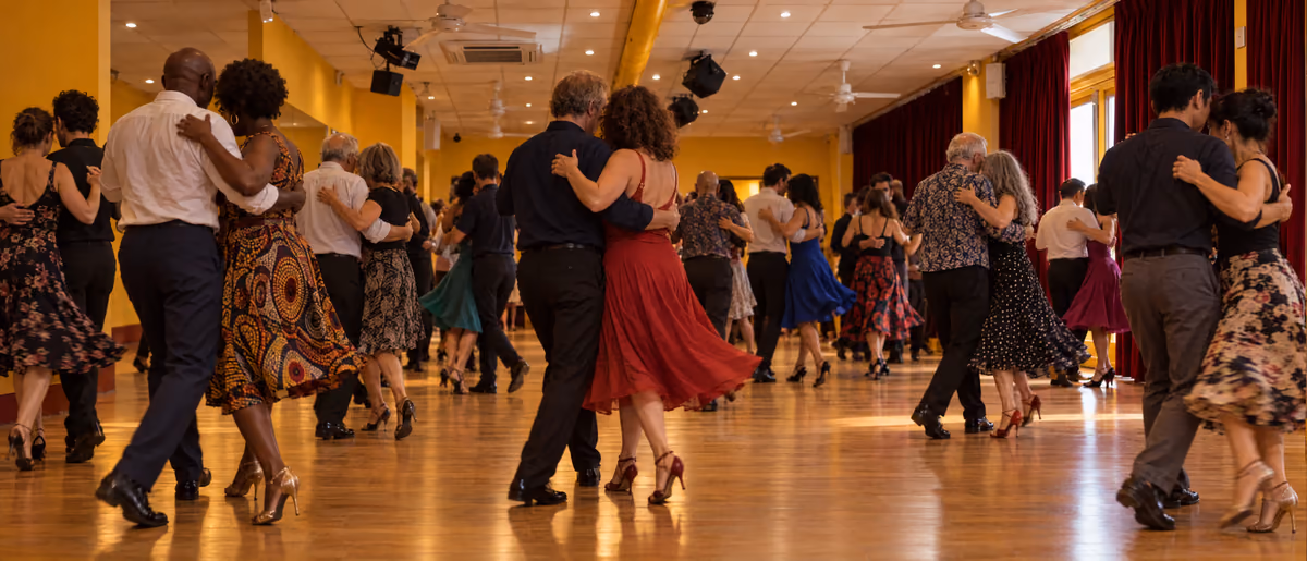 Une dizaine de couples dansent dans la salle jaune un soir de bal, jupes en mouvement sous les rideaux de velours rouge.